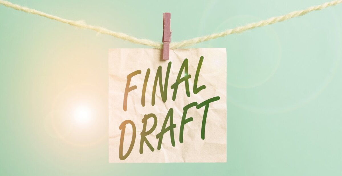 A light green background with the sun shining behind clothes hanging on a line, and a square piece of paper pinned to the line with "Final Draft" written on it.