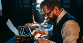 Author wearing in a shirt, tie and waistcoat, typing away on his manual typewritter in a dimly lit office, where old books and antique lightshades are viewable.