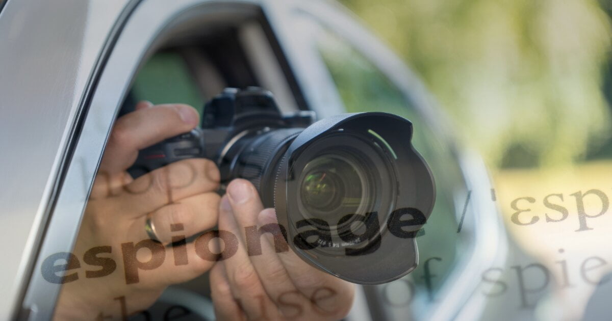 Image of an intelligence officer conducting surveillance by taking pictures from his car seat. Overwritten is the image of Espionage in dictionary form.