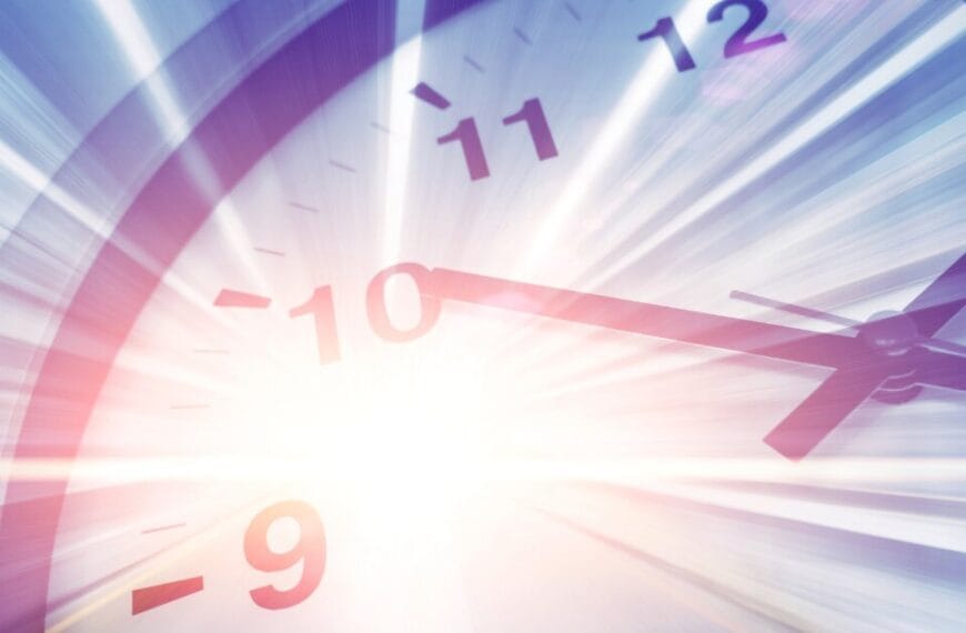 Image of a clock face in white and black at an obtuse angle with a bright flash of light emminating from the centre like a starburst.