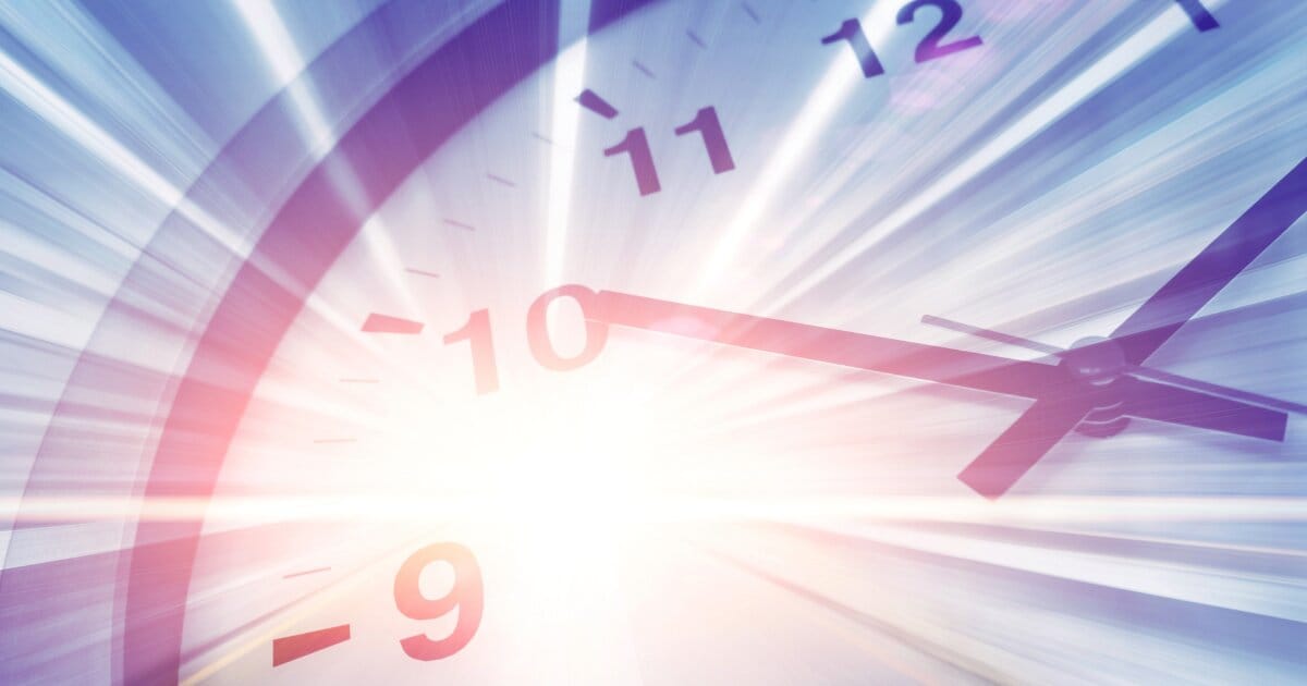 Image of a clock face in white and black at an obtuse angle with a bright flash of light emminating from the centre like a starburst.
